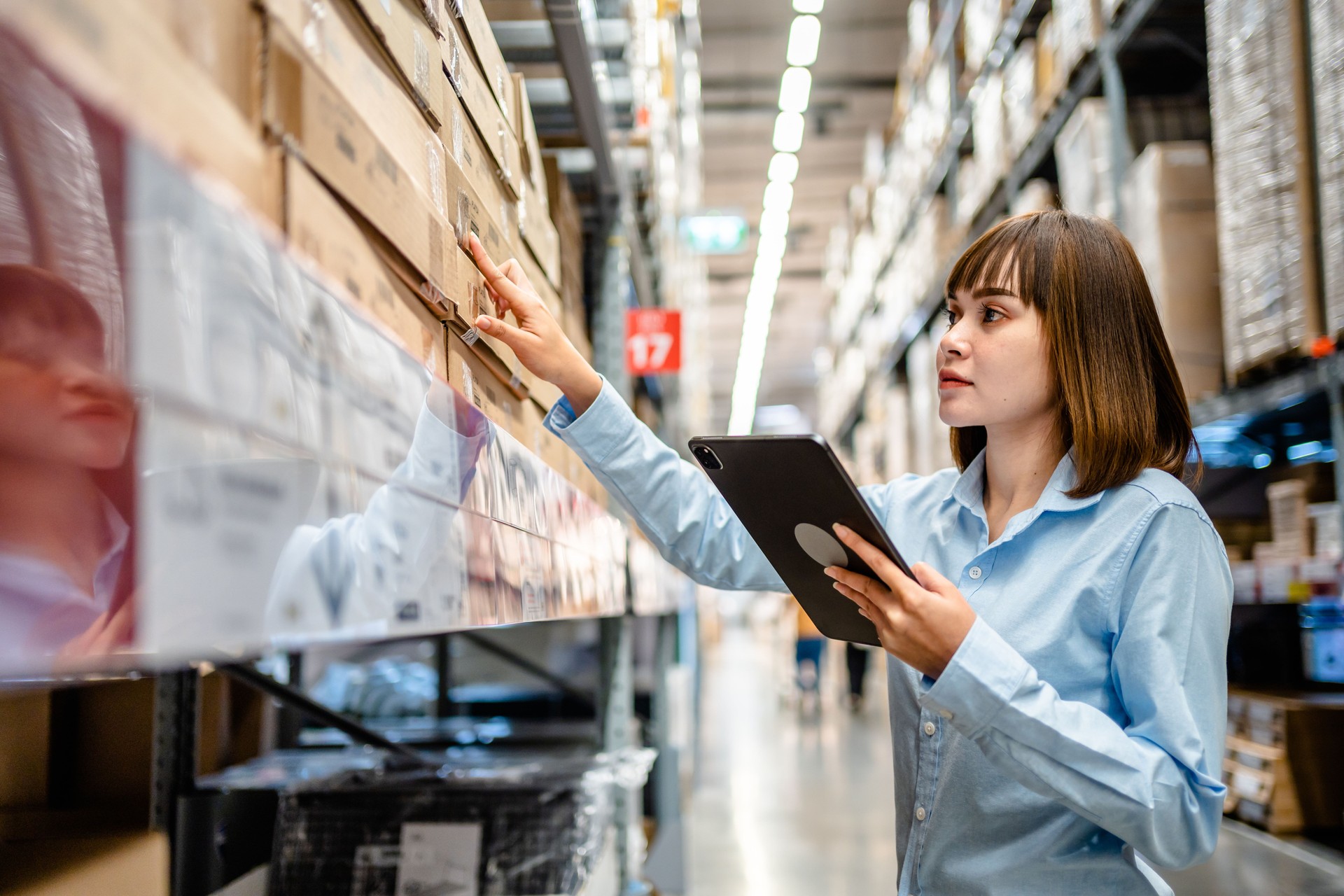 Women warehouse worker using digital tablets to check the stock inventory on shelves in large warehouses, a Smart warehouse management system, supply chain and logistic network technology concept